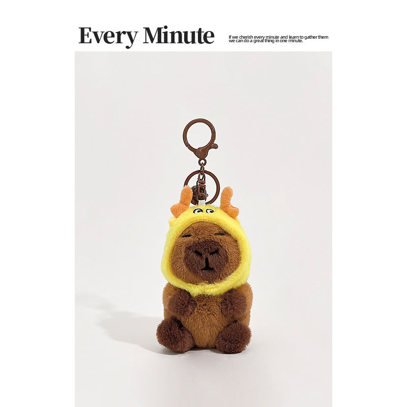 Brown plush capybara keychain wearing a yellow deer hood with small orange antlers and metal clip