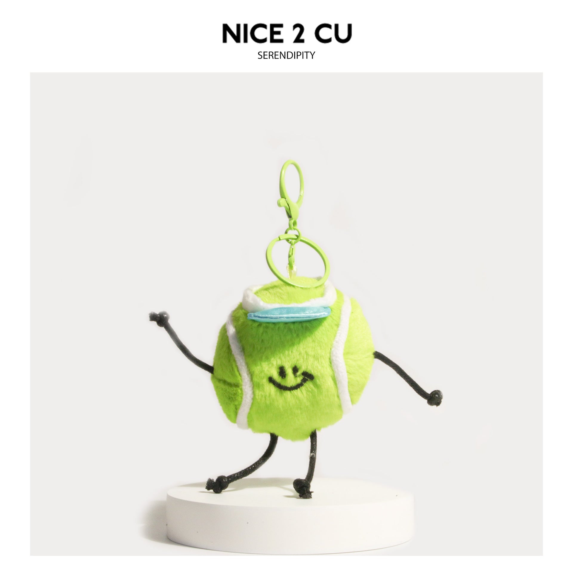 Lime green tennis ball plush keychain charm with light blue visor, embroidered smiley face, and cord limbs in a dynamic pose