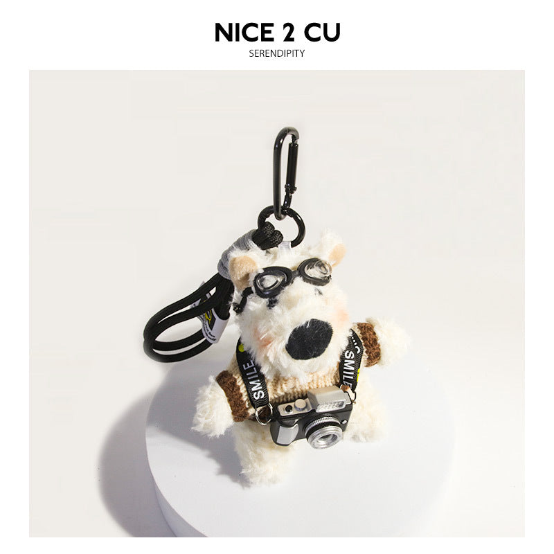Plush white dog keychain charm wearing a latte beige sweater, black goggles, and a tiny camera accessory