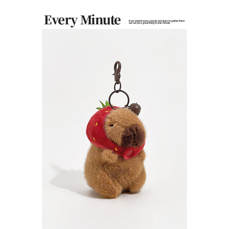 Brown plush capybara keychain wearing a red strawberry hood with green leaf accents and metal clip