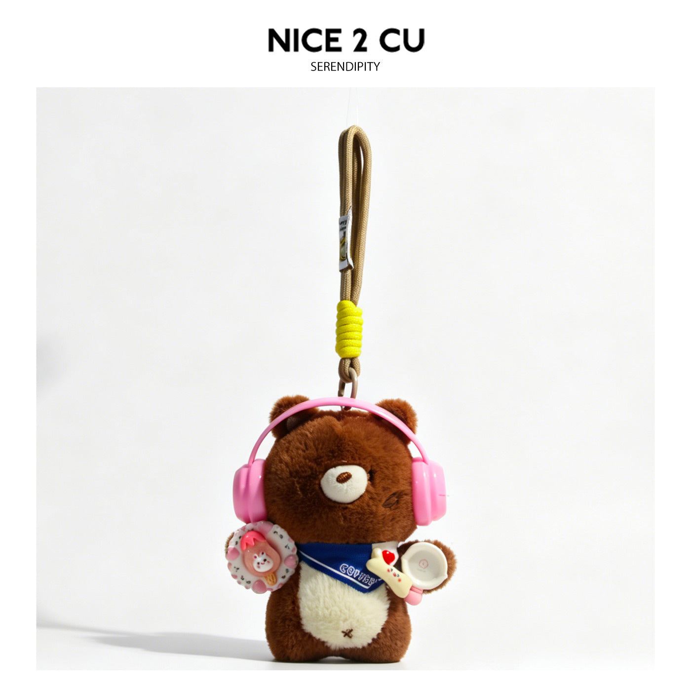 Brown plush bear charm with pink over-ear headphones and blue neckerchief hanging from a beige and yellow braided cord