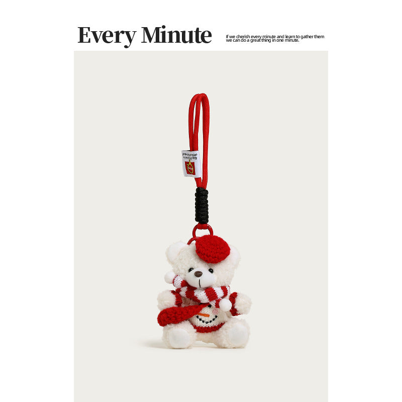 White plush bear bag charm wearing a red beret, striped scarf, and snowman-motif sweater with braided loop strap