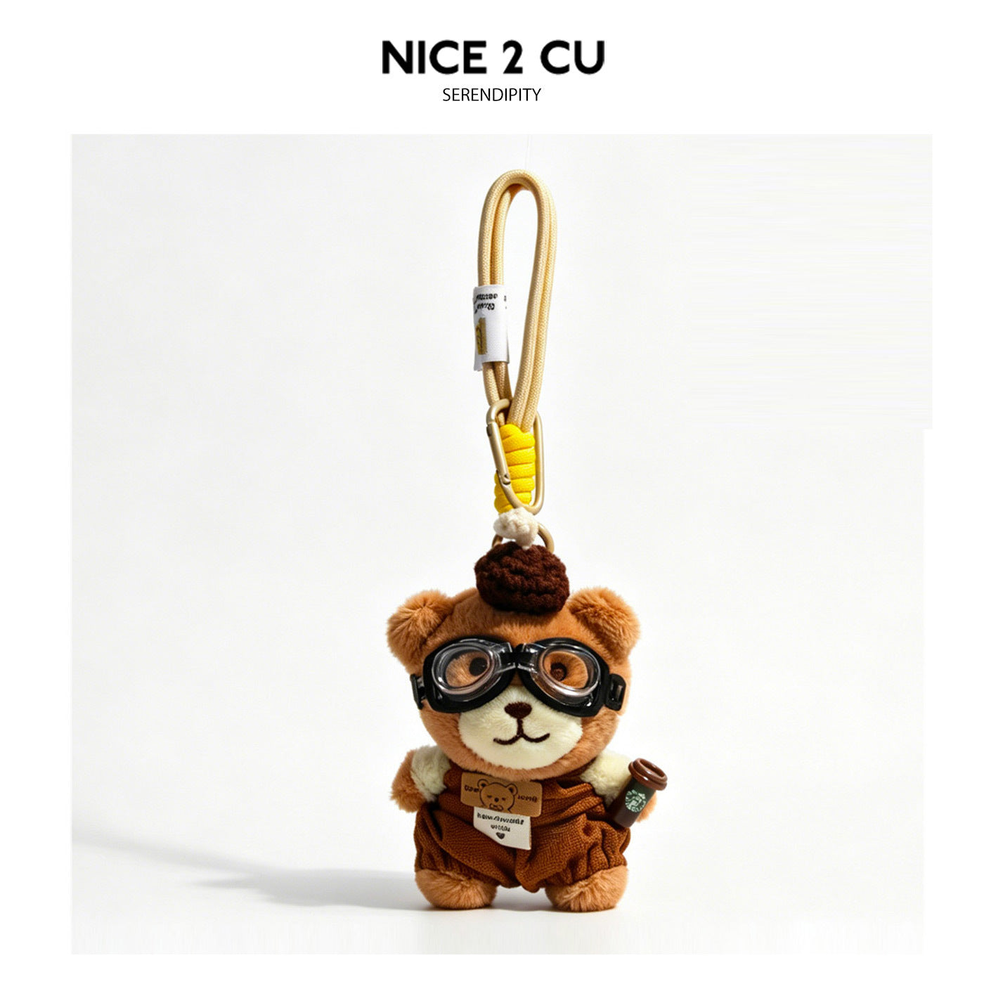 Kawaii plush bear keychain charm wearing dark brown overalls, aviator goggles, and a fluffy hat, holding a miniature beverage