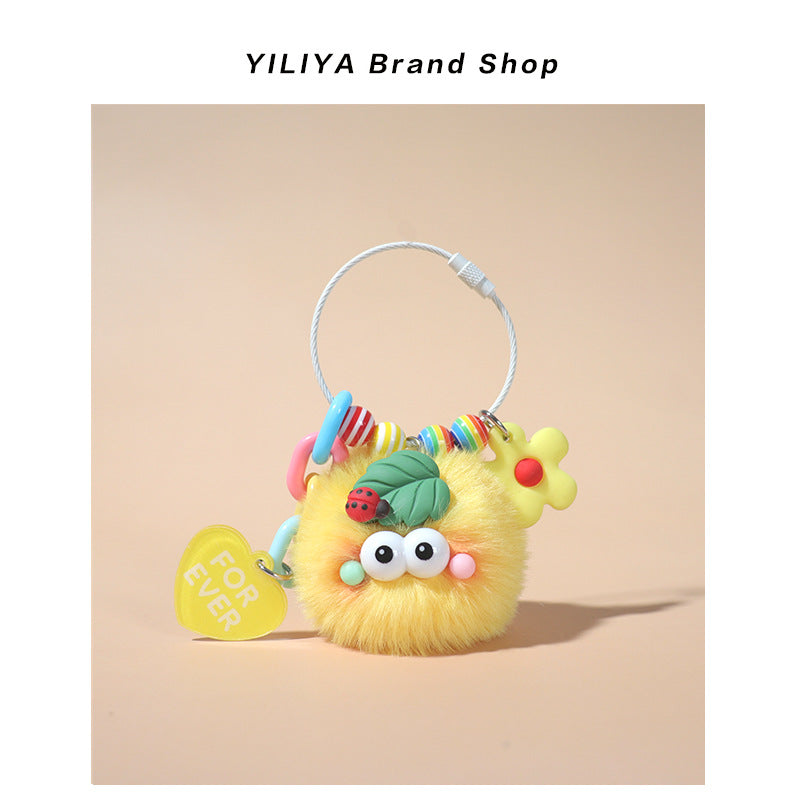 Yellow fluffy pom-pom keychain charm with colorful bead accents, ladybug leaf decoration, and yellow FOR EVER heart tag on la