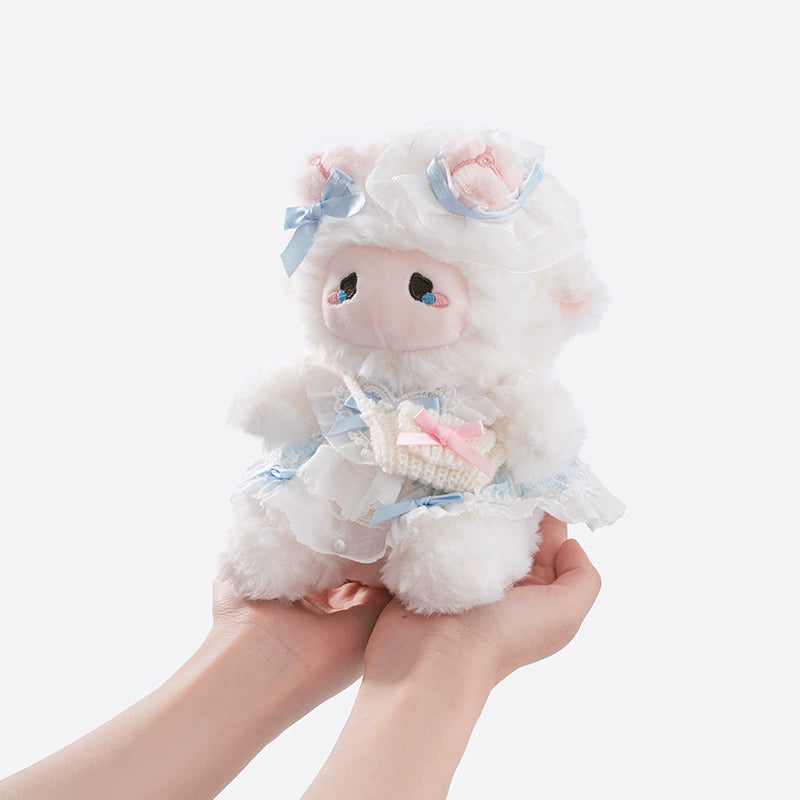 Someone holds the ZEIO Mini Lamb Plush Toy (18cm), a soft sheep doll wearing an elegant lace dress with blue ribbons, matching hat, and carrying a small basket filled with pastel items.
