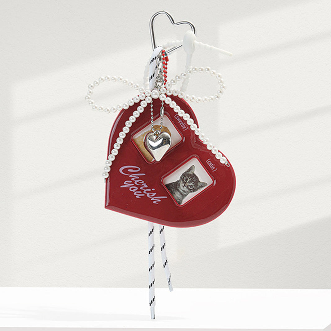 Red heart bag charm with layered pearl bow, two small photo windows, silver heart charm, and striped hanging ribbons