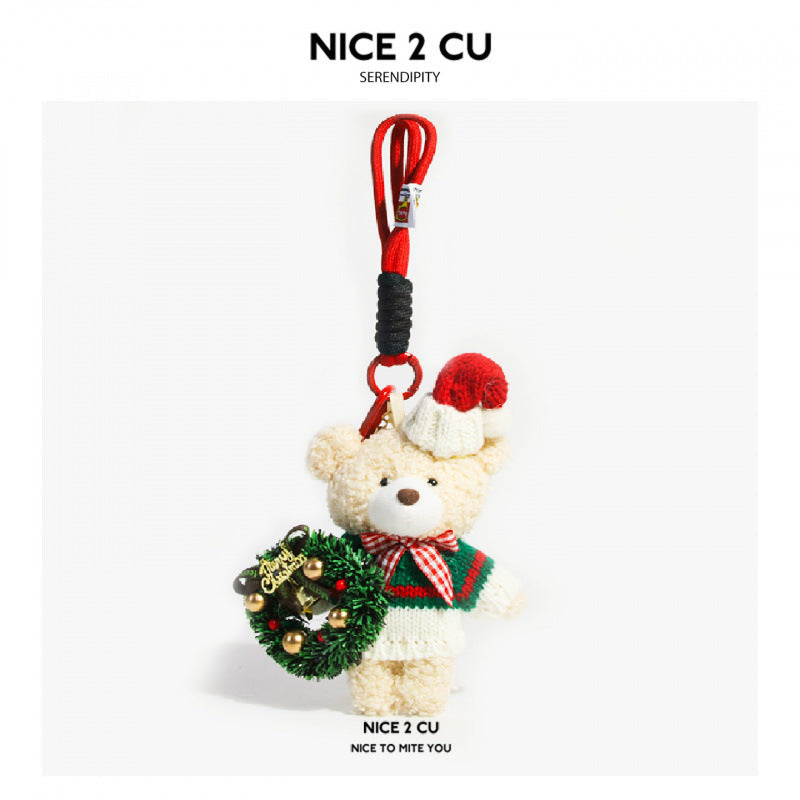 Cream plush bear charm wearing green knit sweater, red Santa hat, and holding a miniature Merry Christmas wreath, with red co