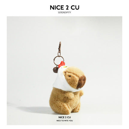 Brown plush capybara keychain wearing a white chicken hood with a red comb and metal keyring