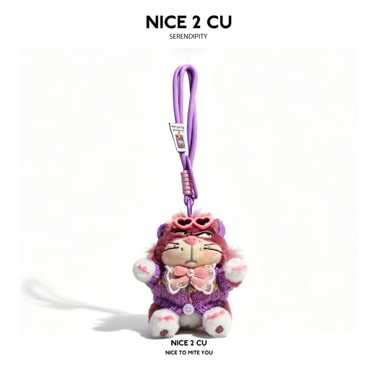Purple-toned cat plush keychain in a purple patterned sweater with a large pink bow on the front
