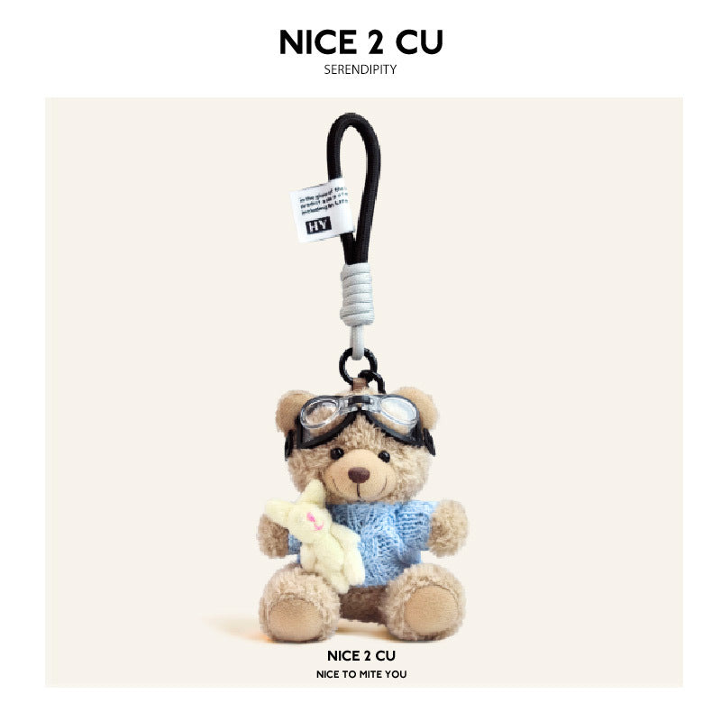 Beige plush teddy bear keychain in light blue knit sweater with aviator goggles, holding a white rabbit