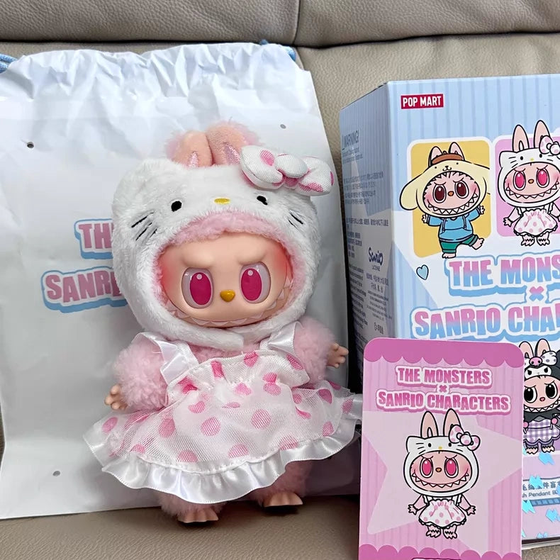 A POP MART LABUBU Hello Kitty and Friends Series Hello Kitty Plush Pendant Figure sits on a couch with themed packaging, a matching cartoon card, and cute kawaii accessories.