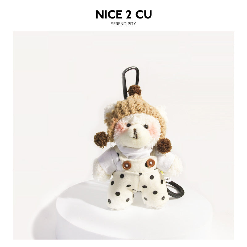 Cream plush bear keychain in polka-dot bib overalls and beige knit hat, black carabiner clip, front view