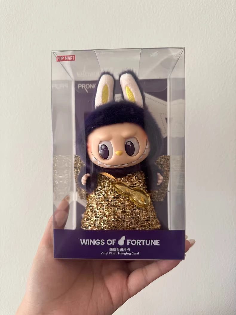 A hand holds a boxed POP MART Labubu × PRONOUNCE Wings of Fortune – Limited Edition Designer Plush Vinyl Toy, showcasing the collectible doll with bunny ears, a gold outfit, and large eyes.