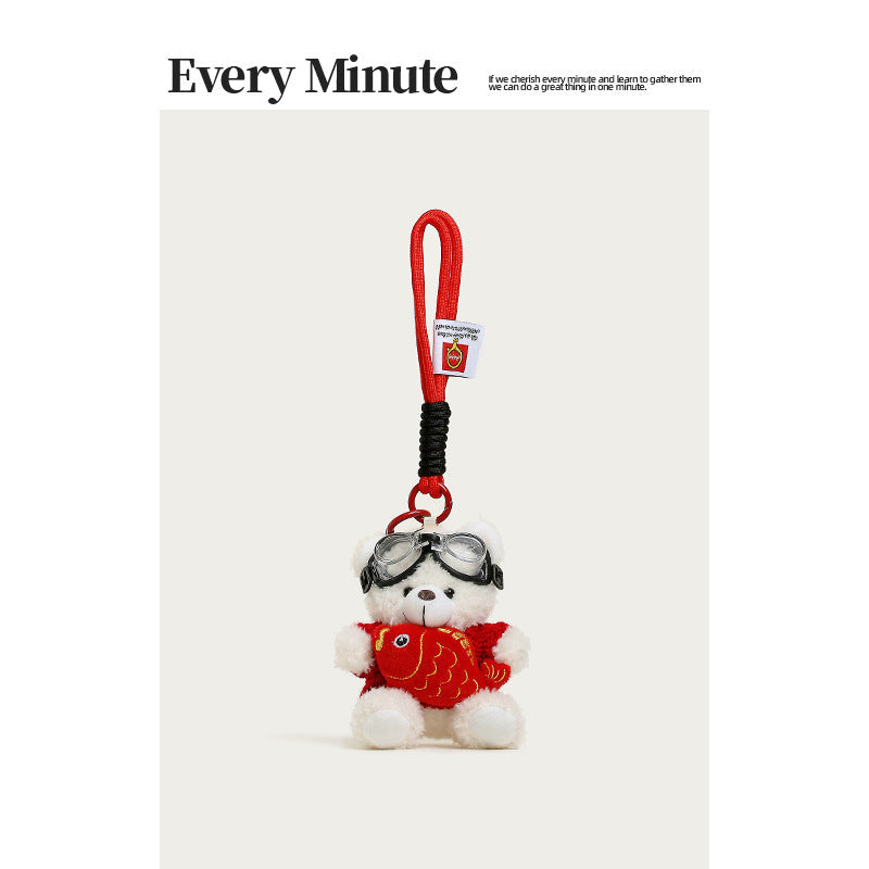 White plush teddy bear hanging charm wearing red sweater and goggles, holding a bright red koi fish plush, red loop strap