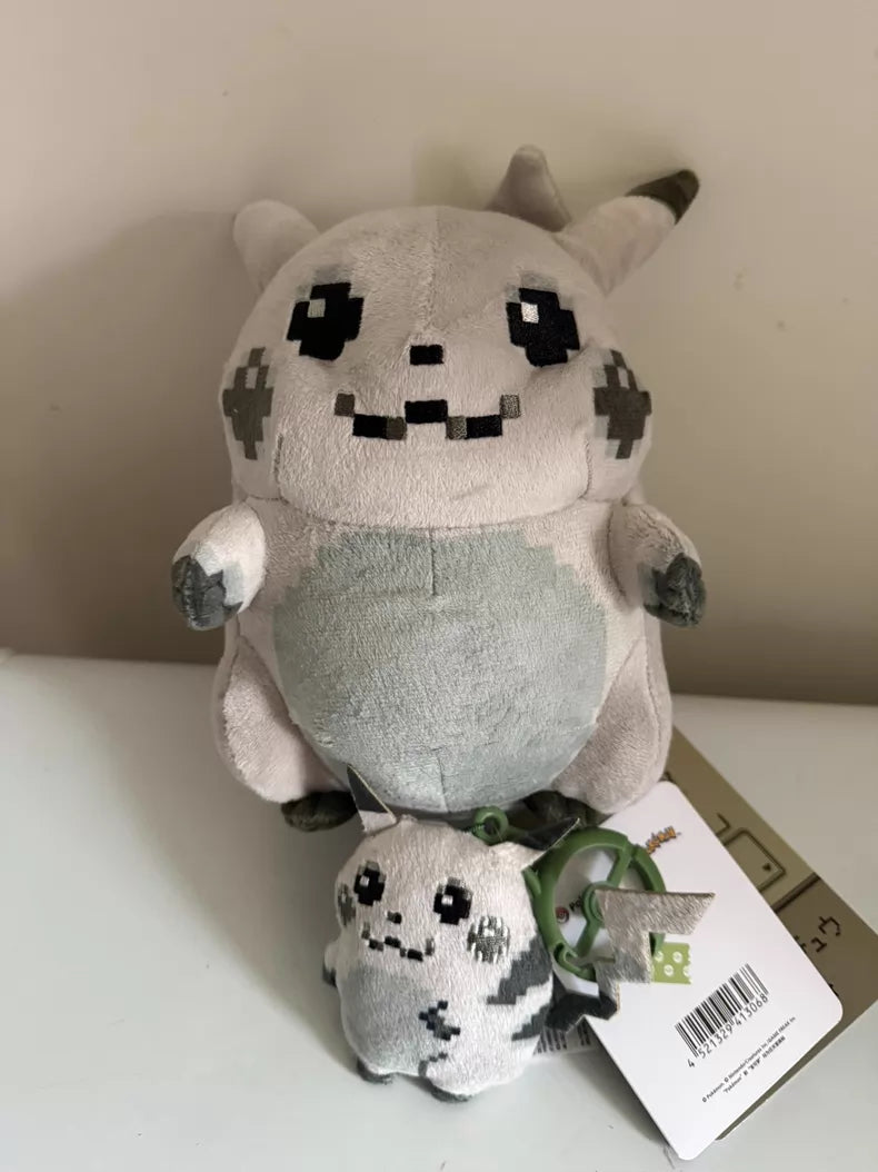 Two plush toys, the ZoDoll Retro 8-Bit Pikachu of Beginnings Plush – Classic Chunky Pokémon 30th Anniversary Pikachu Plush Toy in large and small sizes, are displayed on a white surface, with the smaller plush attached to the larger one and tags visible.