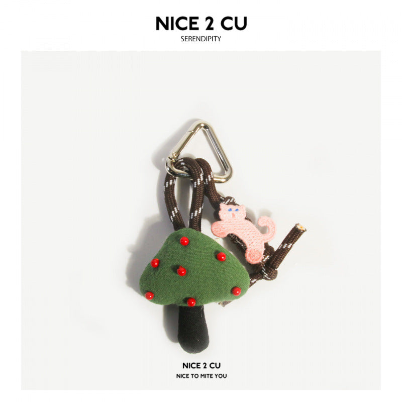 Green mushroom plush bag charm with red dot accents, small pink figure, and metal triangle clasp