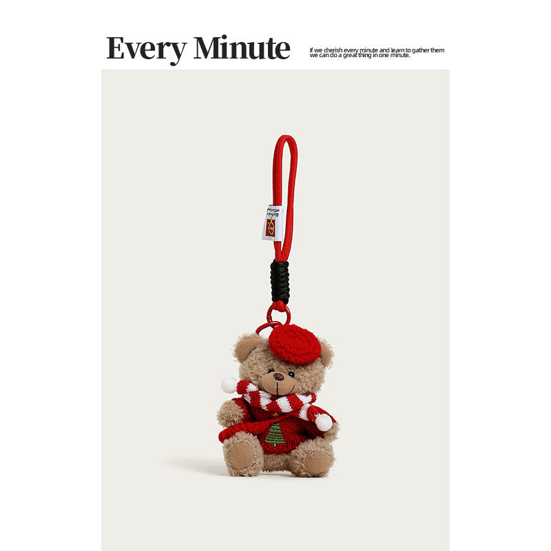 Brown plush bear bag charm wearing a red beret, striped scarf, and Christmas tree sweater motif
