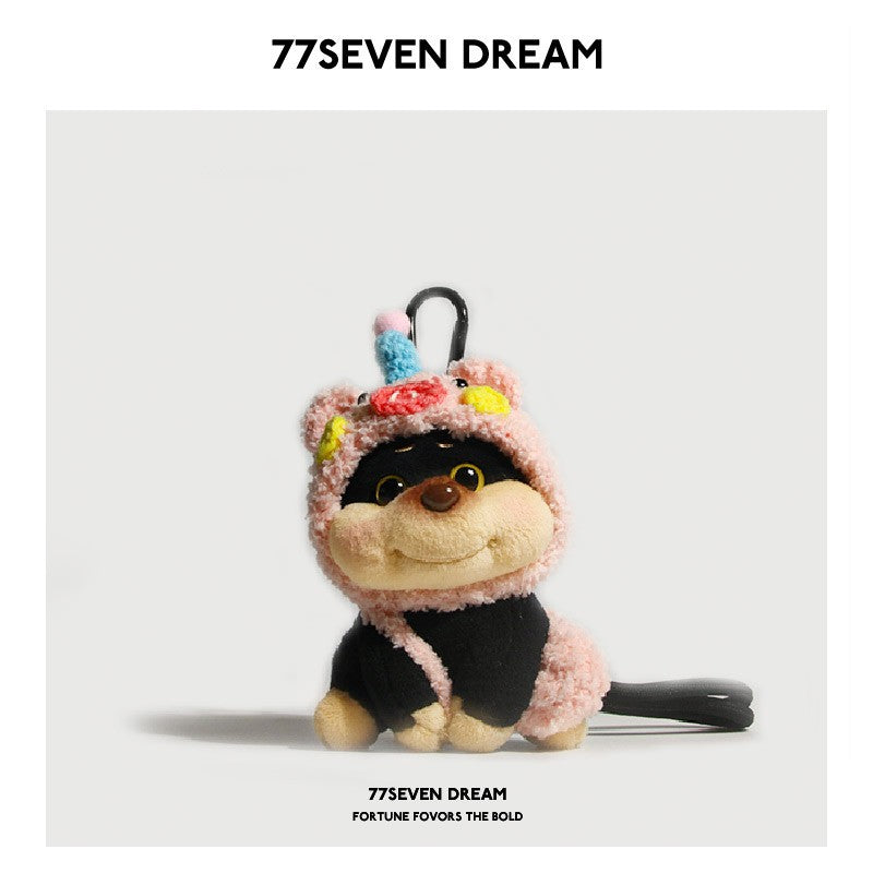 Chubby dog plush charm wearing a pink pig hood with colorful decorative spots and a black hanging strap