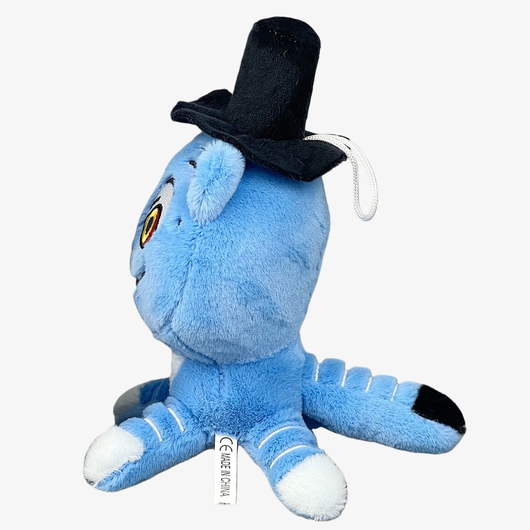 The Demon Hunters Inspired Monster Plush Toy, an anime-style blue creature with yellow and black eyes and a black hat, is shown on a white background. The CE MADE IN CHINA tag is visible.