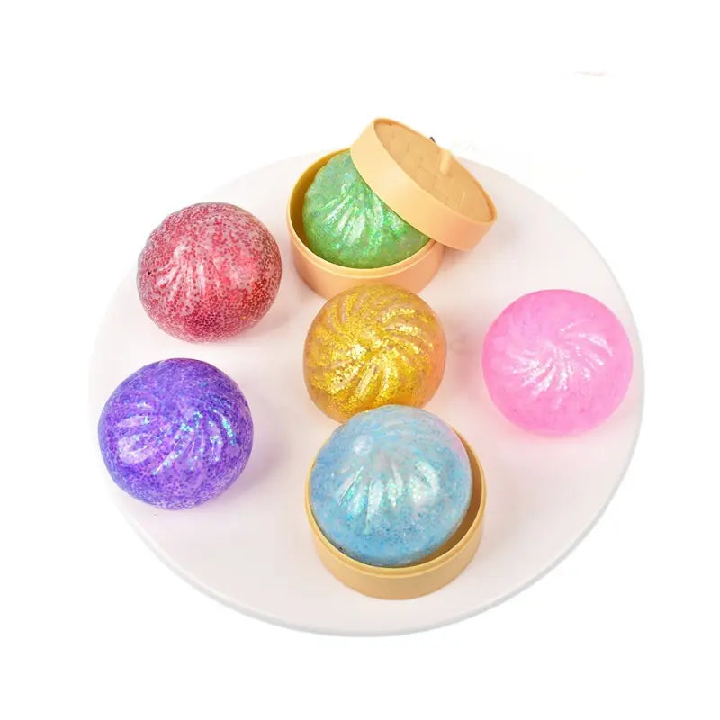 Six colorful, glittery ZoDoll Glitter Squishy Dumpling Sensory Fidget Toys are arranged on a white plate, with one green toy in an open steamer—perfect for a fun and vibrant sensory experience.