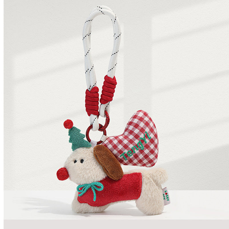 Red-outfit plush dog charm keychain with green bow, red pom-pom hat, and red gingham heart on white rope loop