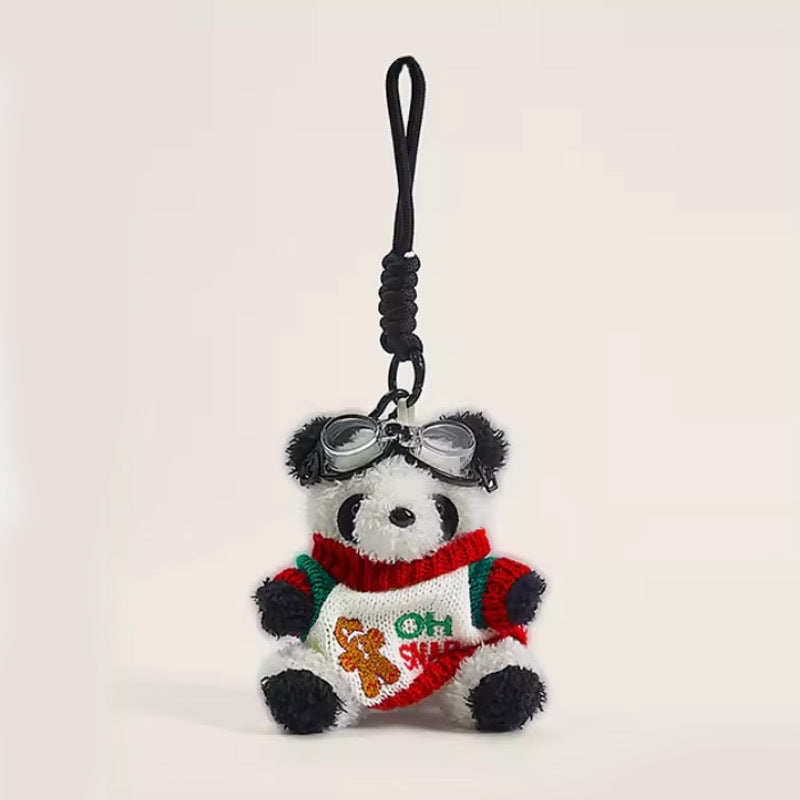Panda plush keychain charm wearing a red and green holiday knitted sweater with miniature silver goggles on its head