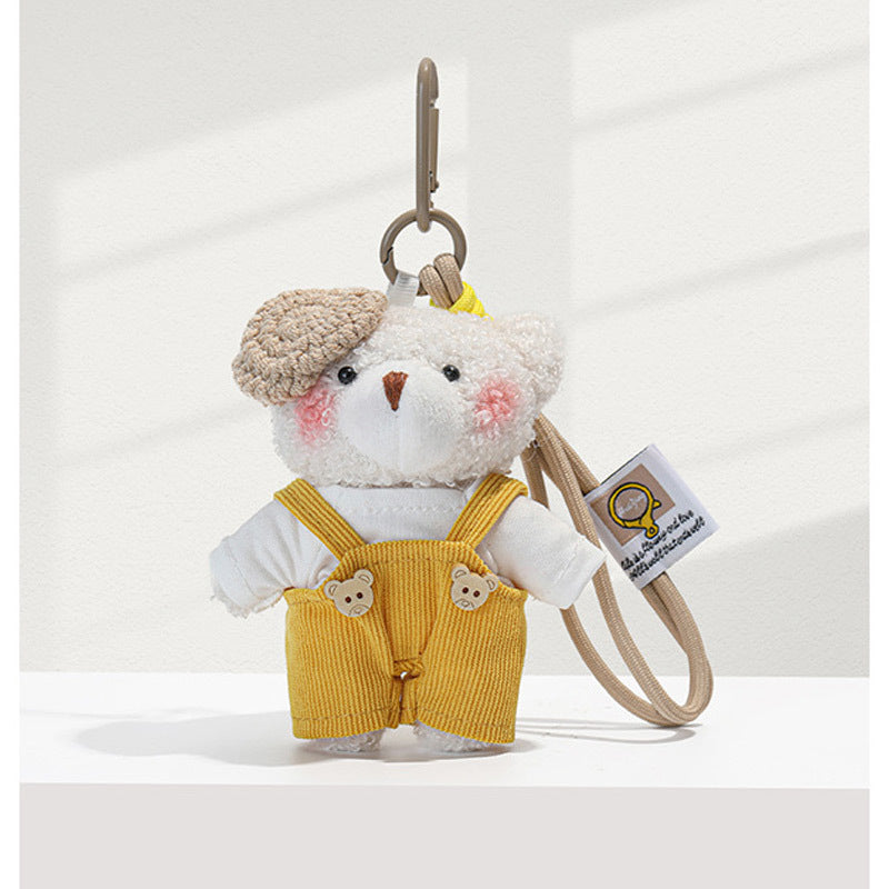 White plush teddy bear bag charm with yellow corduroy overalls, bear-face buttons, and beige carabiner clip