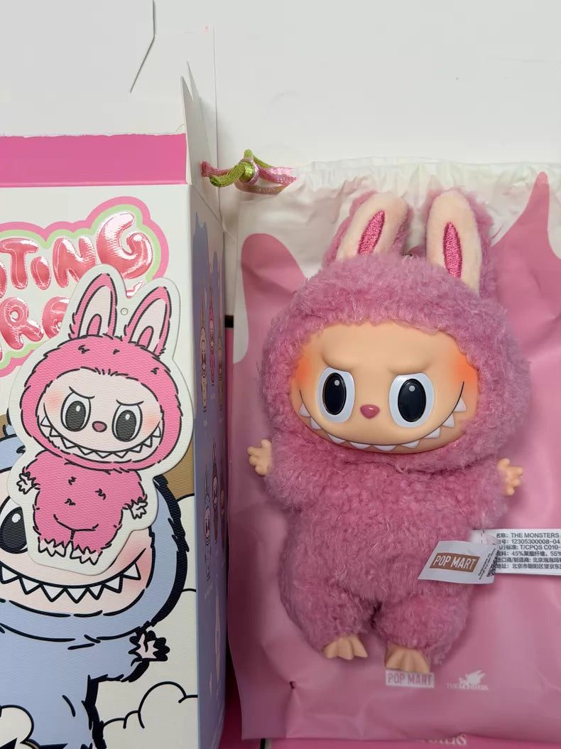 The POP MART Labubu “Lychee Berry” Plush Keychain features The Monsters character in a pink fleece bunny costume with big eyes and a wide grin, displayed beside its illustrated matching packaging.