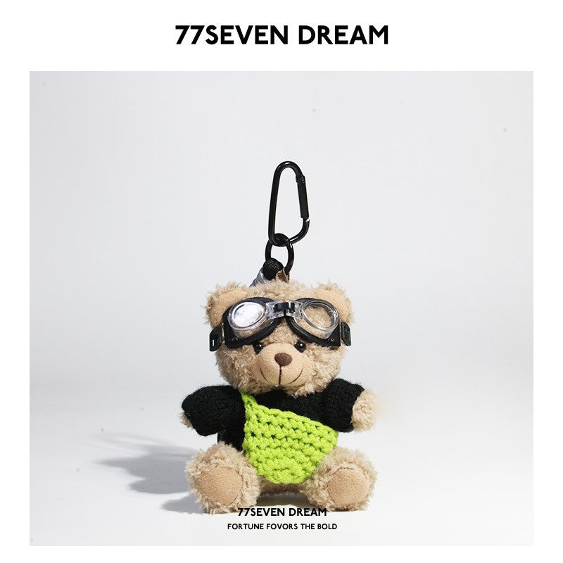 Beige plush teddy bear keychain in black knit sweater with green knitted front pouch accent and aviator goggles