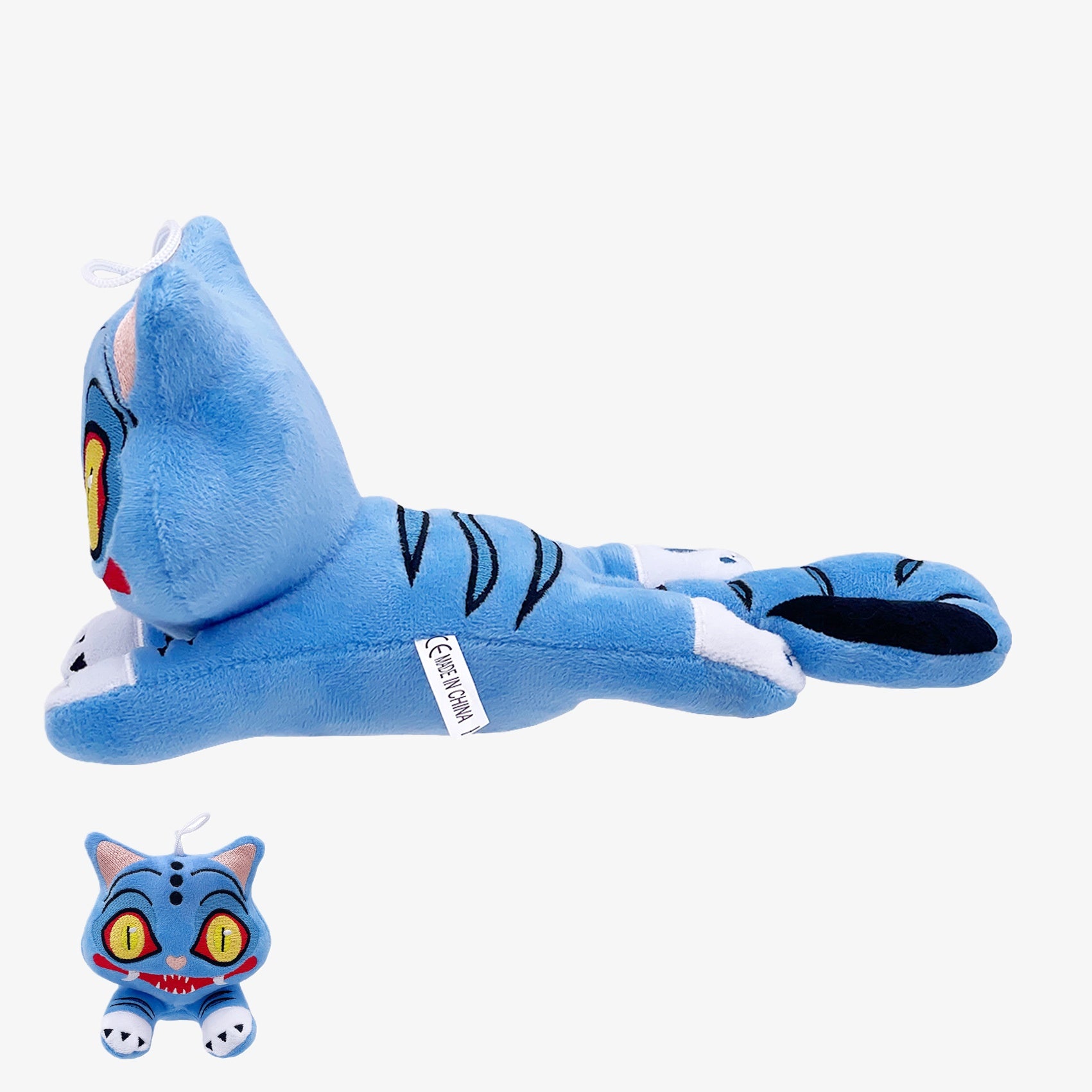 The Demon Hunters Inspired Monster Plush Toy—a blue anime-style creature with yellow eyes, stripes, white accents, and a hat—lies on its stomach; an inset shows its face and red mouth.