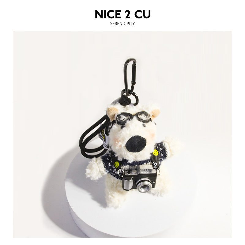 White terrier plush keychain in a navy and black patterned sweater with aviator goggles and a miniature camera