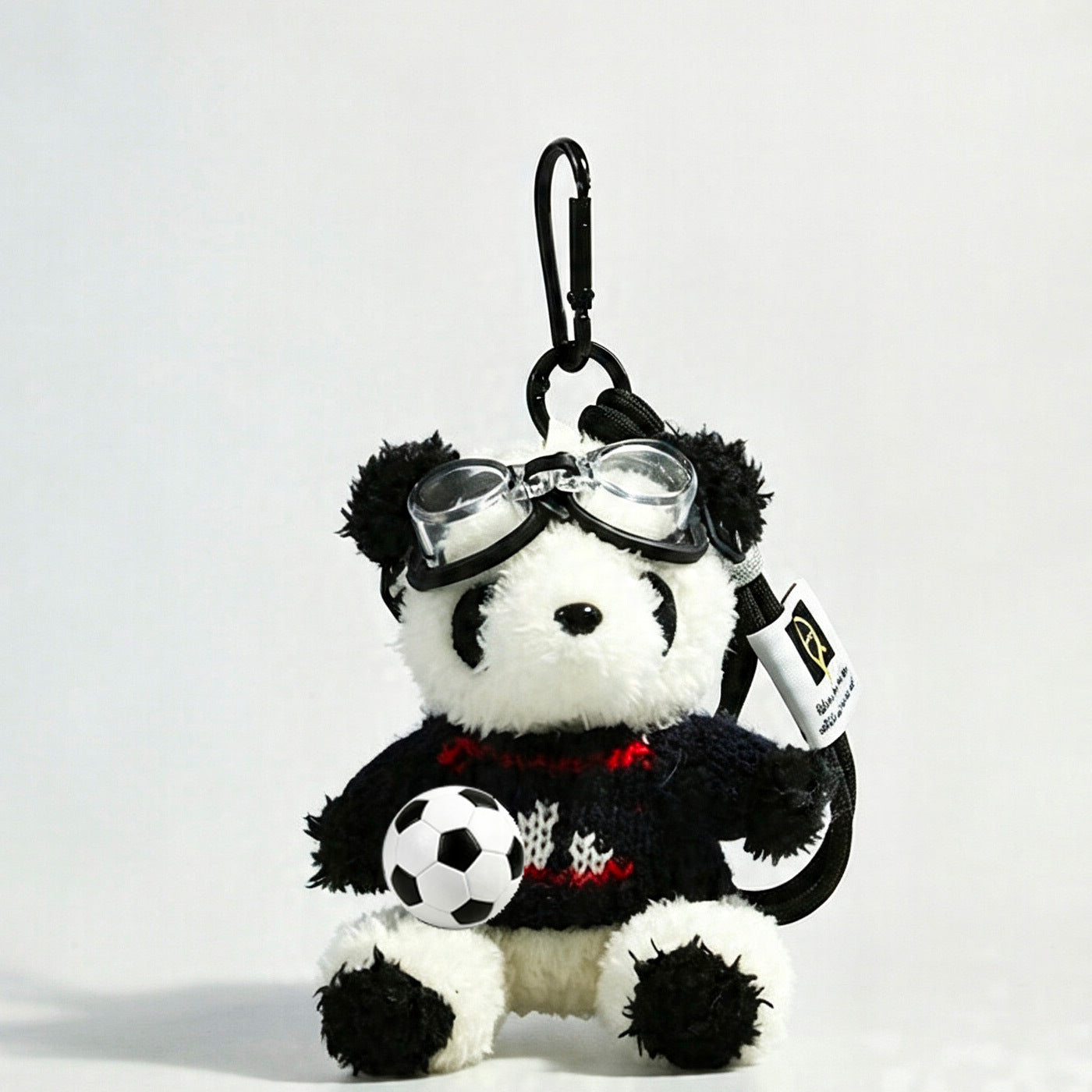 Panda plush bag charm wearing a black knit sweater with red-and-white graphic detail and clear goggles