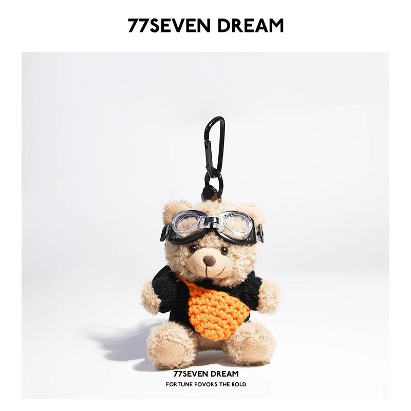 Beige plush teddy bear keychain in black knit sweater with orange knitted front pouch accent and aviator goggles
