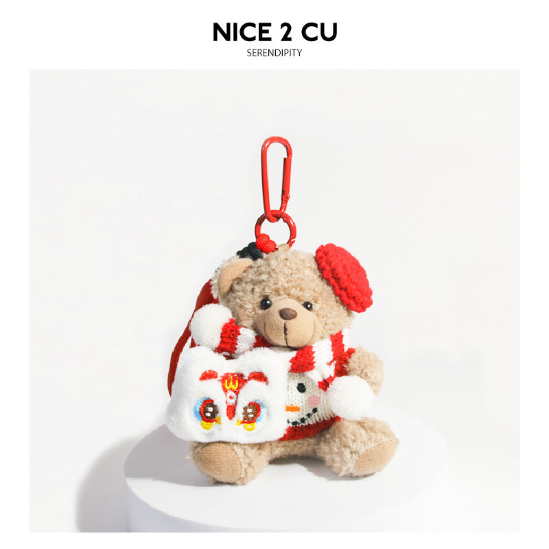 Tan curly plush bear keychain charm in red-and-white knit outfit holding a lion dance face panel with red carabiner clip