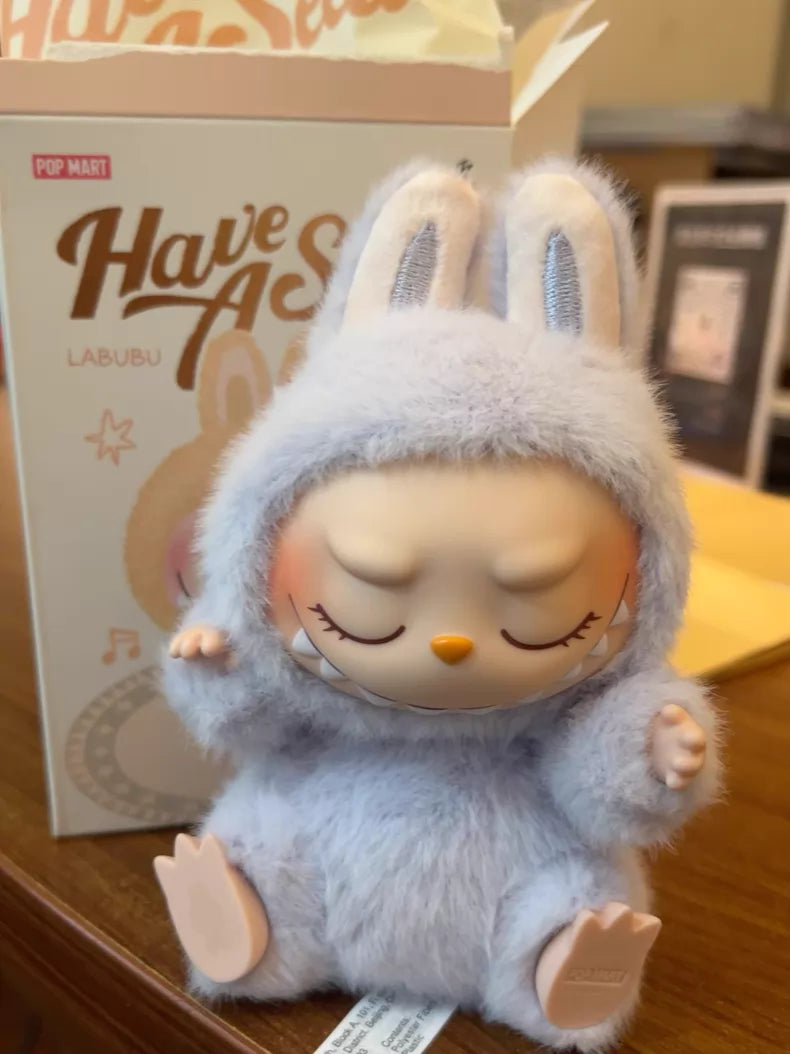 The Labubu “Zizi” Plush Keychain from POP MART’s Have a Seat Series features the character in a light purple bunny suit with closed eyes, presented in its branded packaging—a must-have for The Monsters Collection fans.
