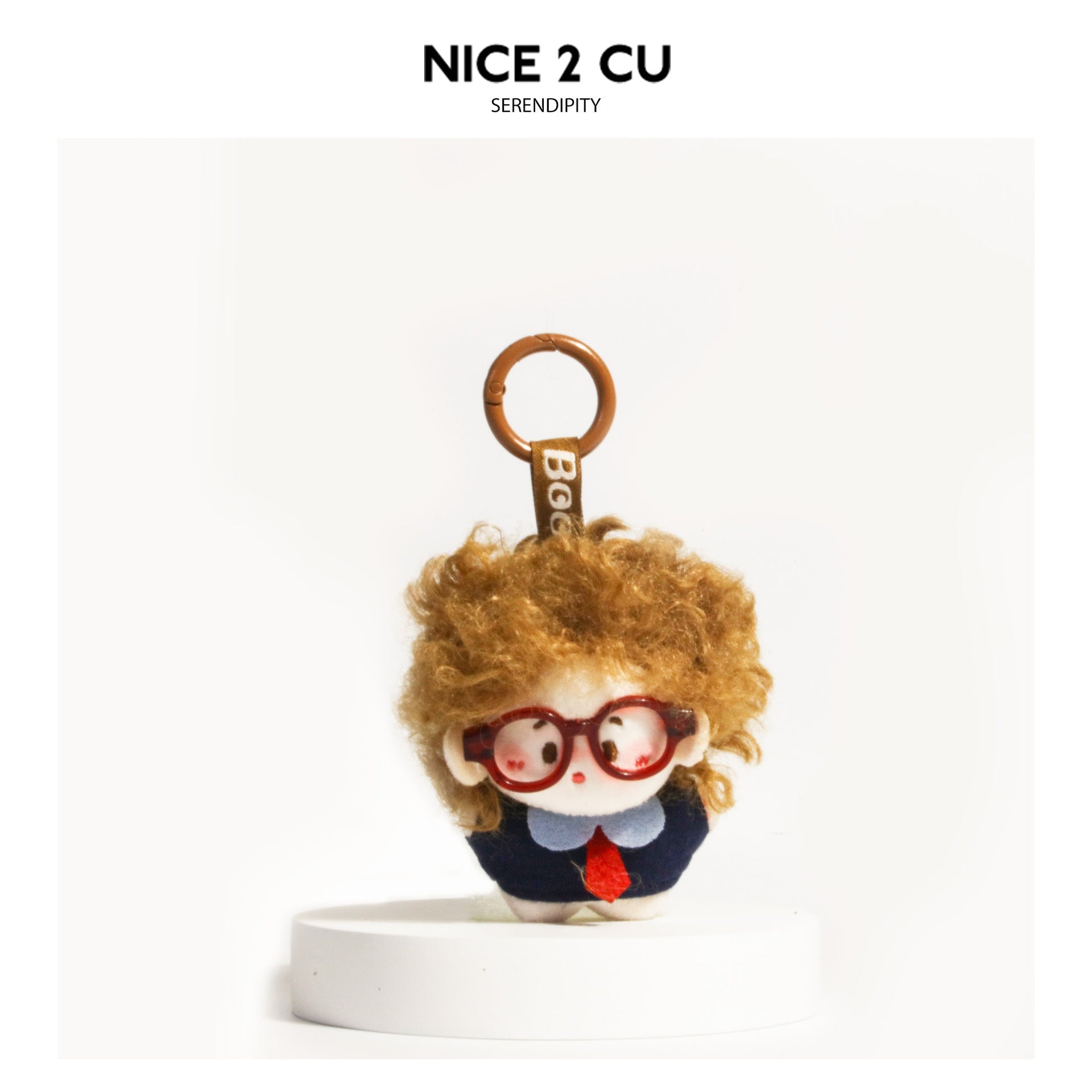 Brown curly-haired chibi plush doll keychain with red glasses and navy outfit on brown carabiner ring