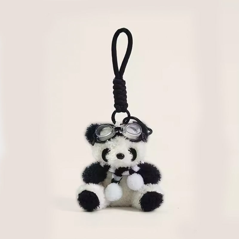 Panda plush charm with black and white pom-pom scarf and silver goggles on braided cord strap