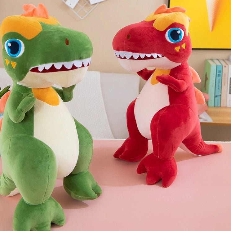 Two ZoDoll T Rex Plush Dinosaur Soft Stuffed Animal Toys, in green and red, stand upright on a pink surface in a bright room with books and decor visible in the background.