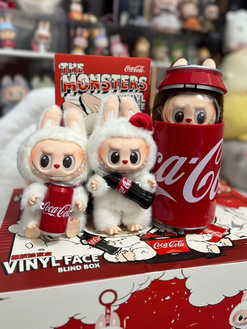 Three Labubu Secret Edition “Mysterious Guest – Coca‑Cola” Plush Keychain collectibles by POP MART, dressed as white bunnies, pose on a Coca‑Cola display box; one is partially inside a large Coca-Cola cup.