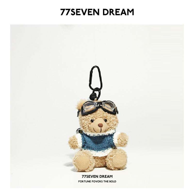 Beige teddy bear plush keychain wearing a blue-and-white knit top with aviator goggles and a carabiner clip