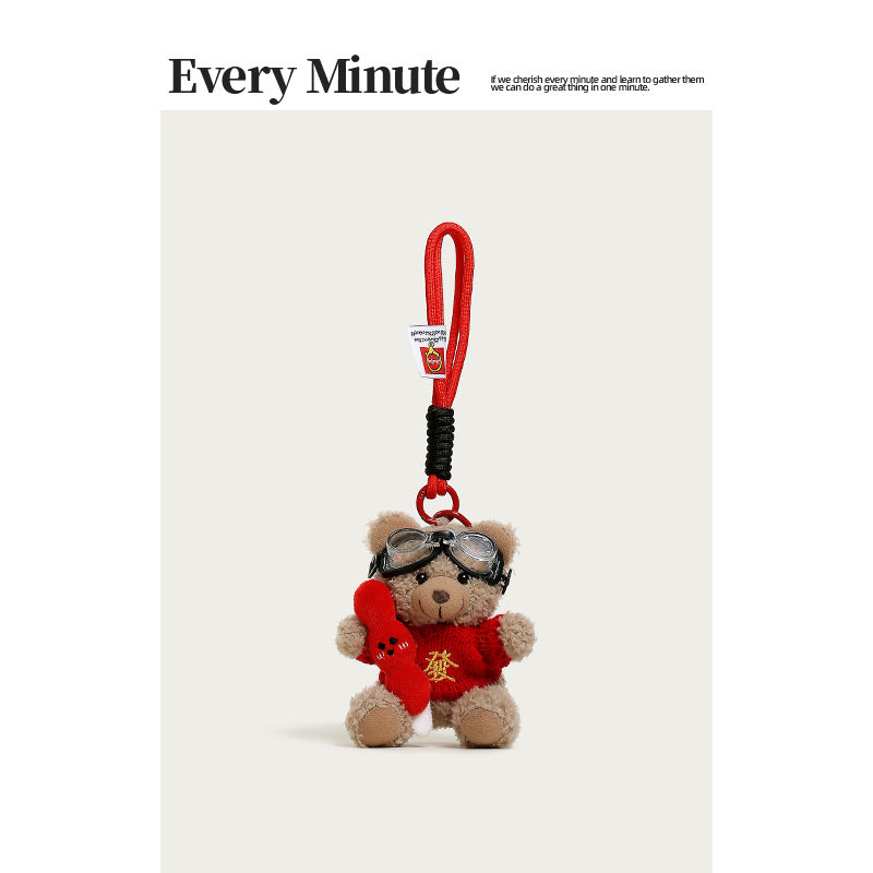 Brown plush teddy bear keychain charm in red gold-character sweater with aviator goggles holding a red tanghulu skewer access