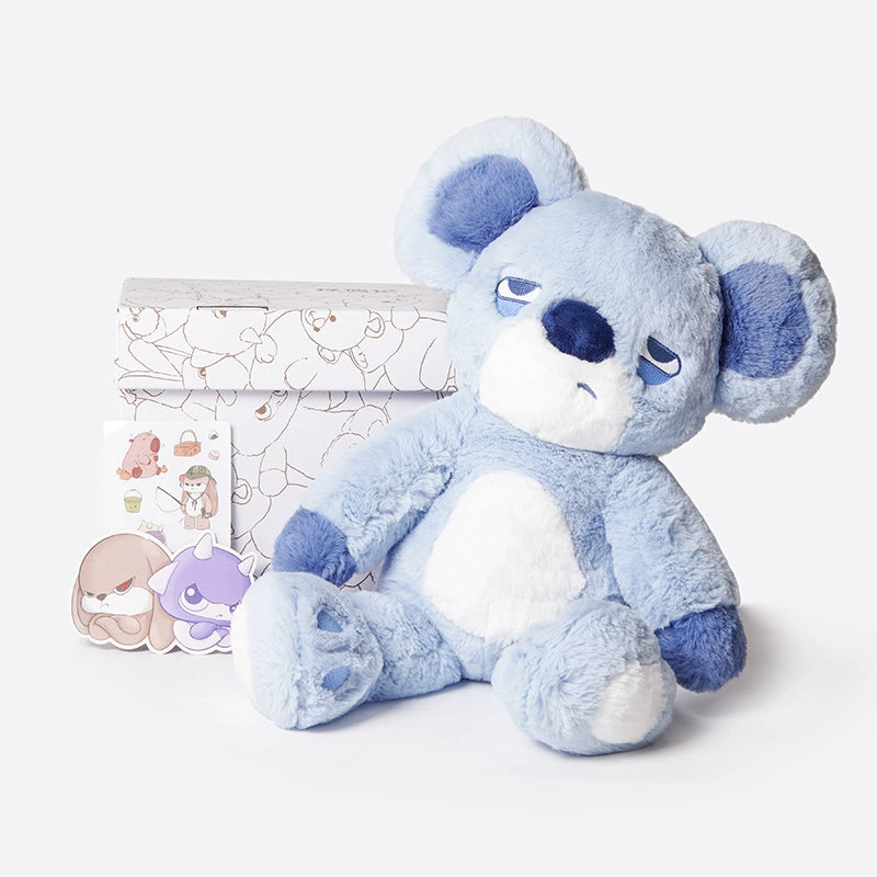 The ZEIO Koala Plush Toy 38cm—a soft, large stuffed koala with a relaxed expression—sits before a patterned box and cartoon stickers, making it a cozy cuddle companion and adorable nursery décor.