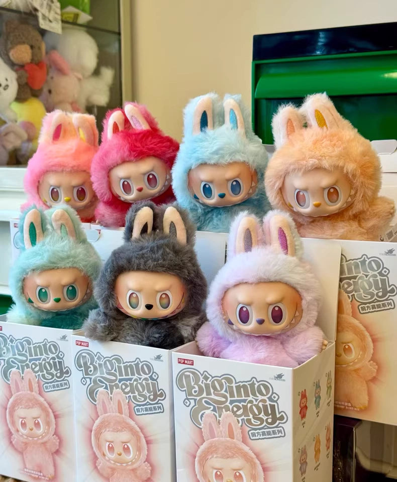 Eight pastel plush dolls with bunny ears, some in BIMTO GREY boxes, are displayed alongside the POP MART Labubu “Big Into Energy” 6‑Piece Plush Keychain Set—Complete Collection: Love, Happiness, Loyalty, Serenity, Hope & Luck—with other plush keychains.
