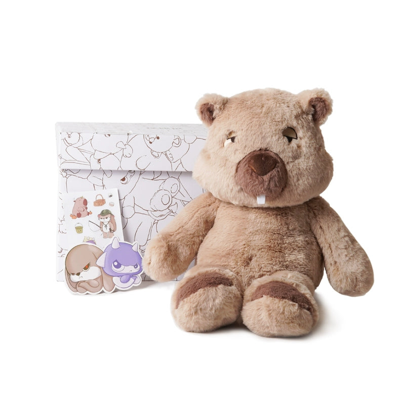 A ZEIO Wombat Plush Toy—48cm large and ultra-soft with a mini doll—sits before a white illustrated envelope and three cartoon stickers.