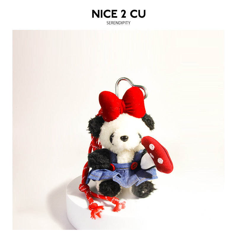 Black and white panda plush bag charm with red bow, denim skirt, and red polka-dot mushroom accessory