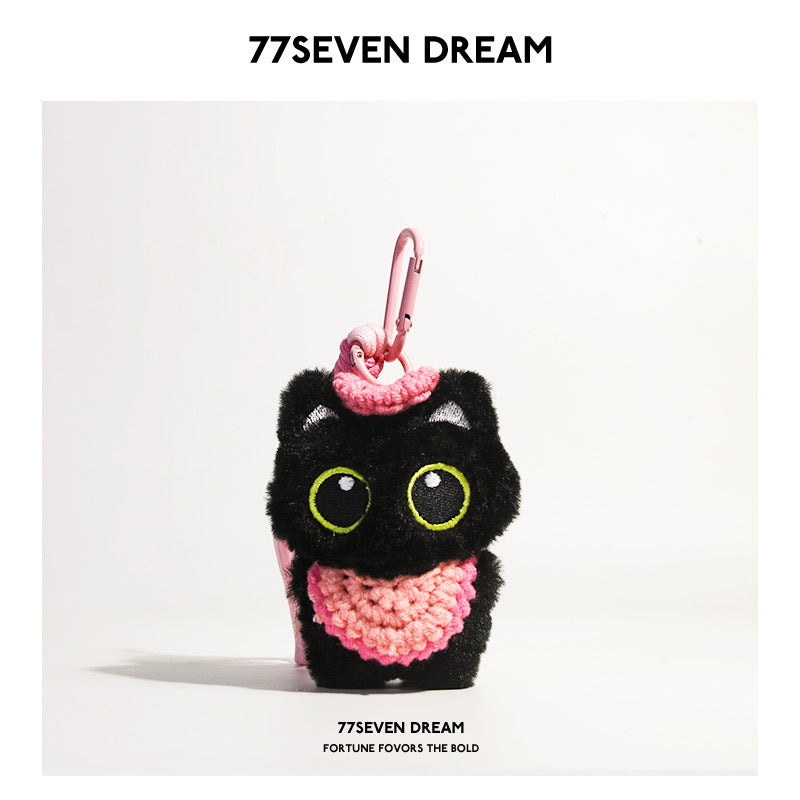 Black cat plush charm with green-outlined eyes and pink crocheted bib, pink carabiner clip