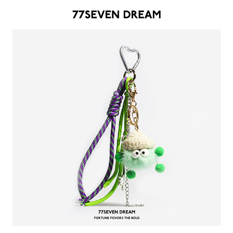 Mint green fluffy plush monster keychain with crocheted hat, googly eyes, heart carabiner, and braided green-purple cord