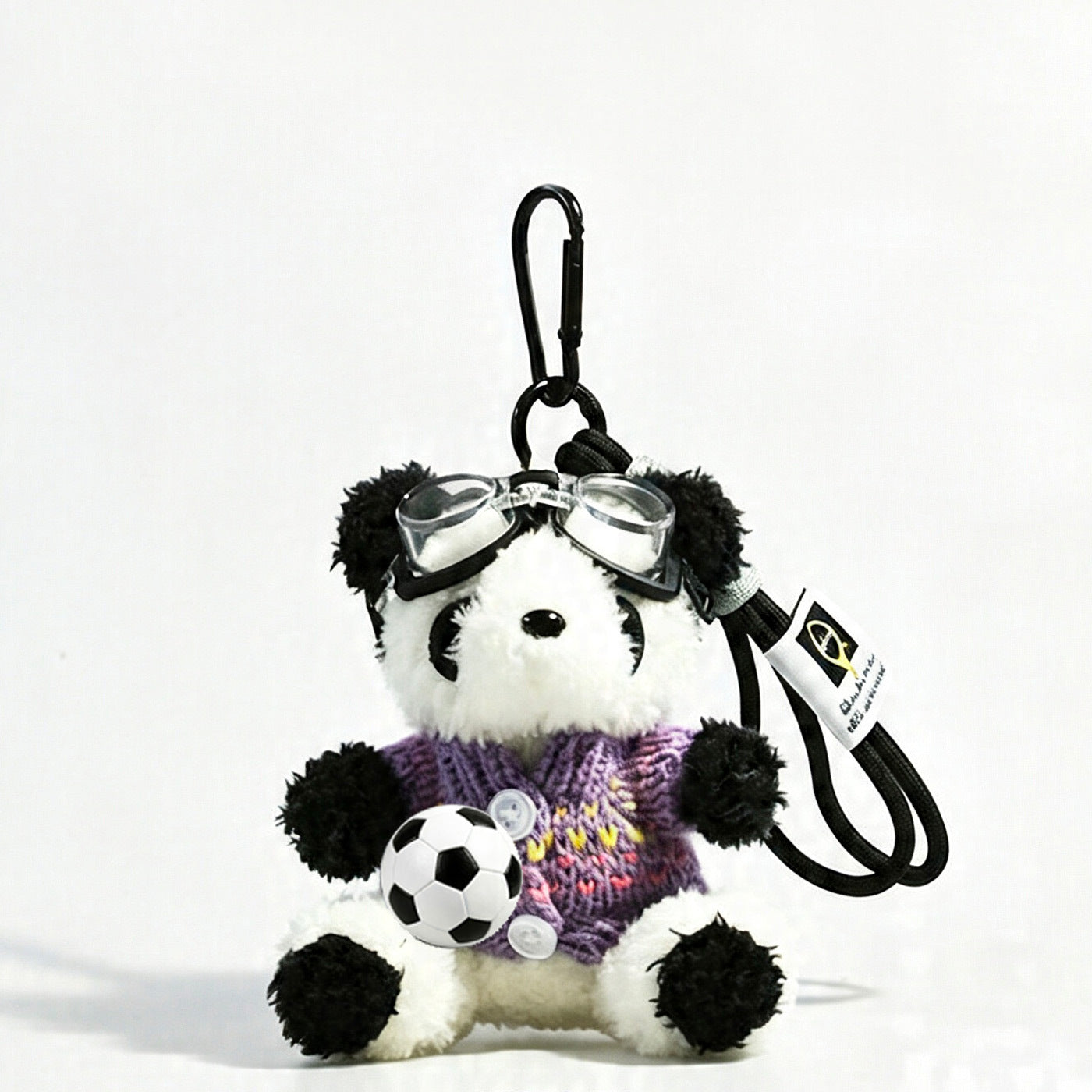 Panda plush keychain in a purple knit sweater with multicolor accent details and clear goggles, holding soccer ball