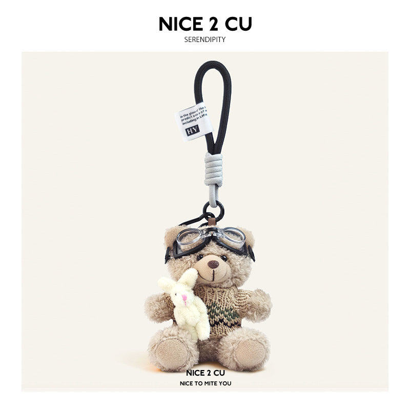 Beige plush teddy bear keychain in khaki-and-brown striped knit sweater with aviator goggles, holding a white rabbit