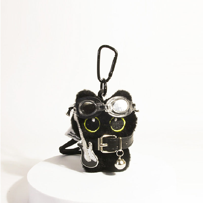 Black cat plush keychain with large yellow-outlined eyes, silver goggles, belt, and guitar charm